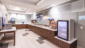 A modern kitchen area with a digital menu display, a coffee machine, and a refrigerator.