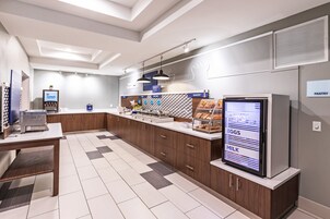 Un área de cocina moderna con un menú digital, una cafetera y un refrigerador.
