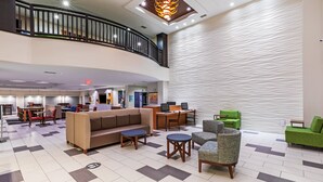 A spacious lobby with a checkered floor, a curved staircase, and a reception desk.