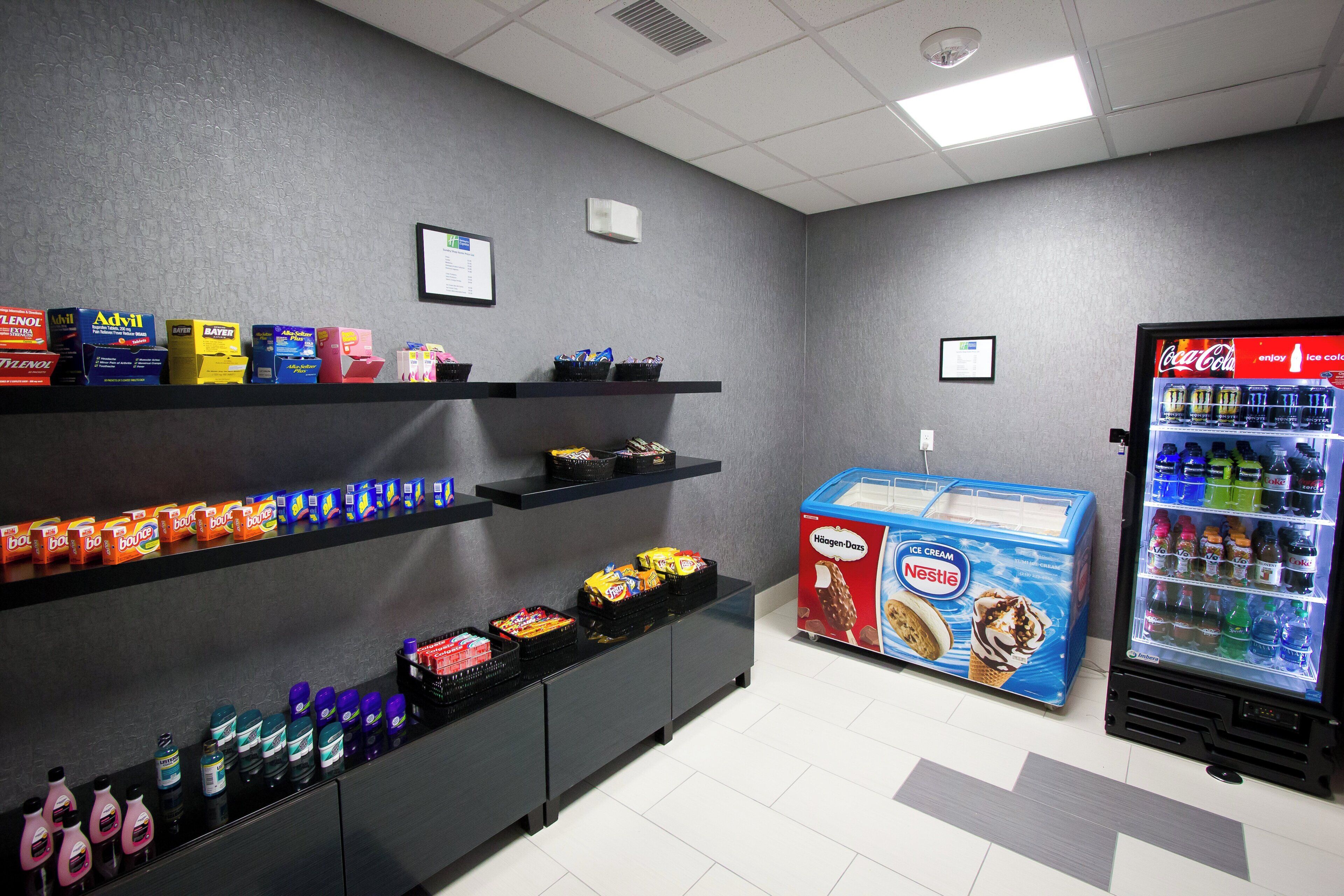 A vending machine with various beverages and snacks, shelves with boxes of products, and a wall-mounted sign.