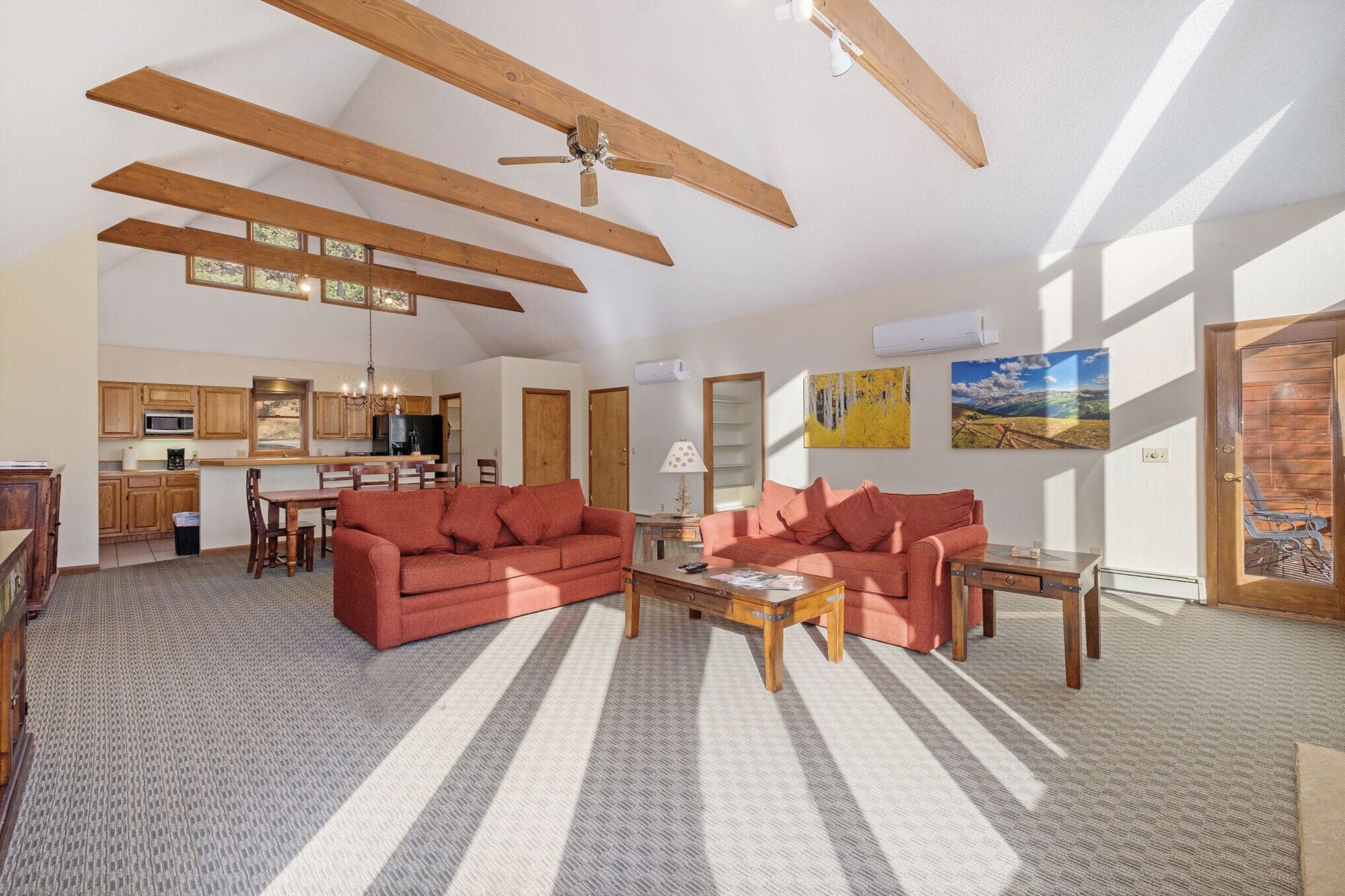 A spacious living area with a large sofa, a coffee table, and a kitchen in the background.