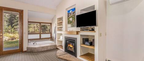 Una sala de estar moderna con chimenea, televisor y estanterías empotradas.