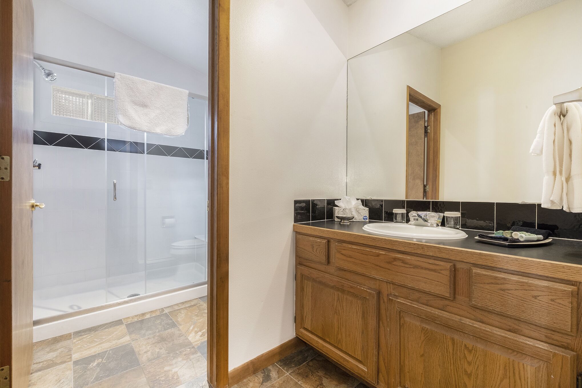 Une salle de bain dotée d’une douche à parois de verre, d’un meuble-lavabo en bois et d’un grand miroir.