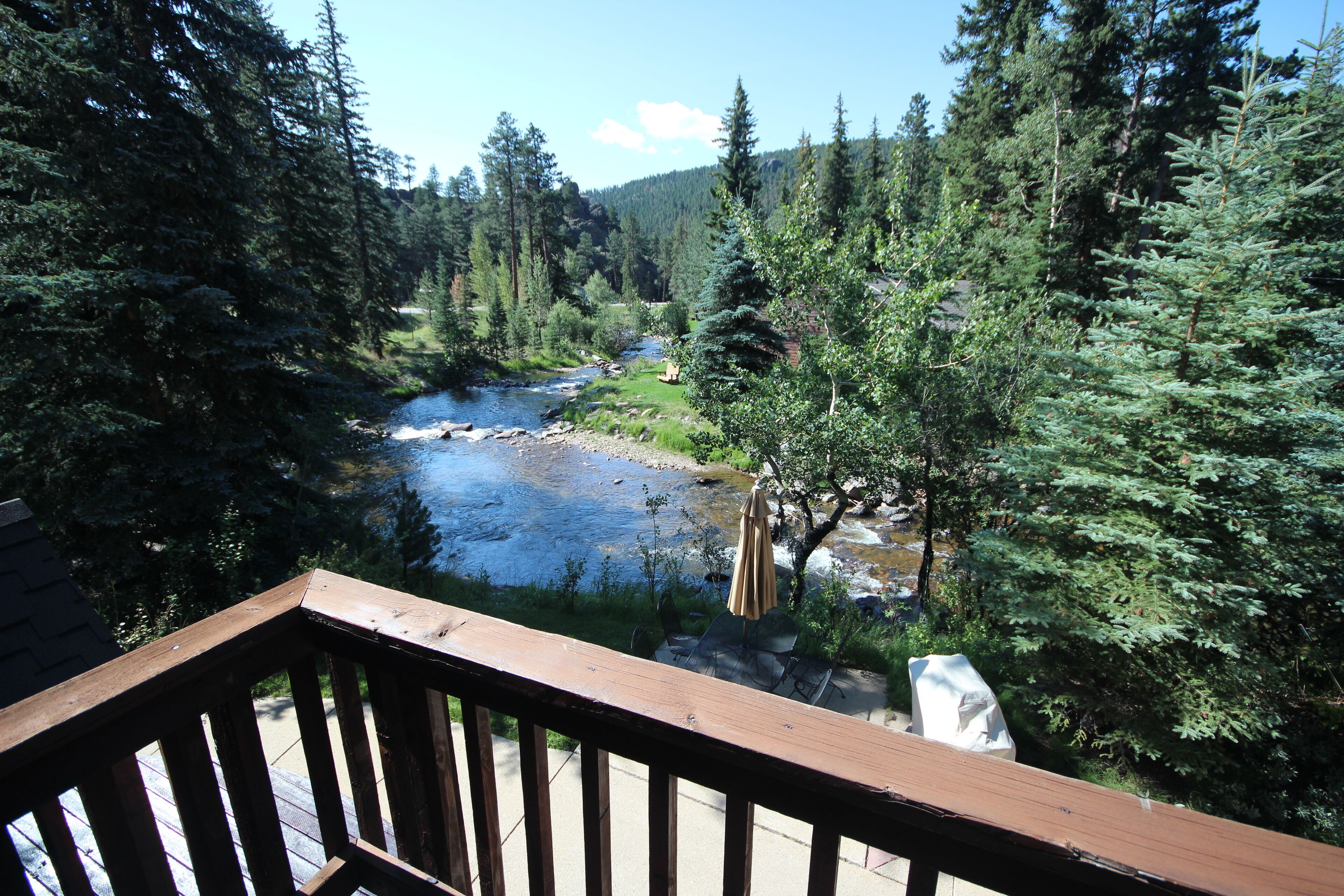 A deck with a view of a river and forest.