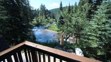 A deck with a view of a river and forest.