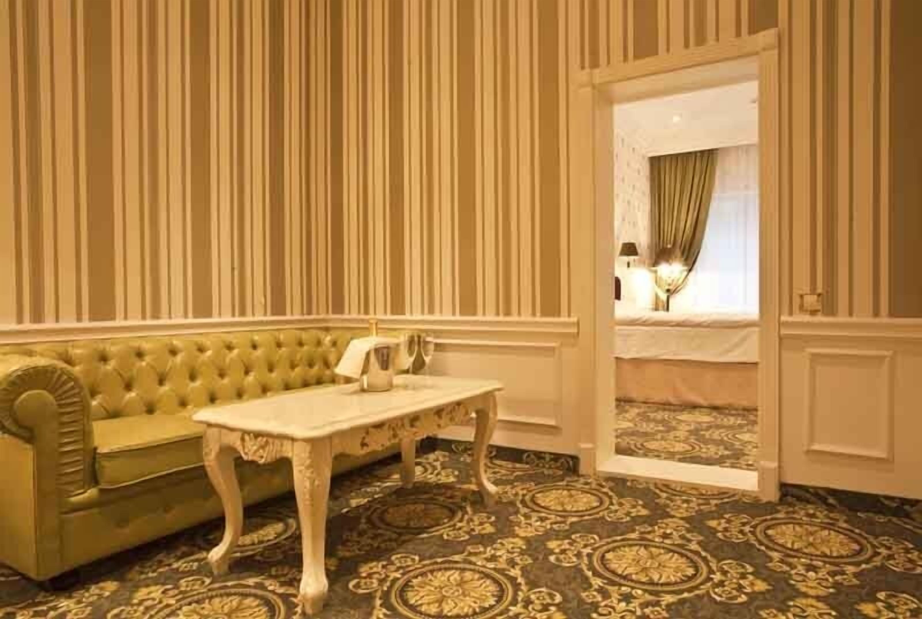 A room with a green sofa, a white table, and a patterned carpet.