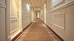 A long, narrow hallway with patterned carpet, white walls, and doors on both sides. - Royal Congress Hotel (Kyiv)