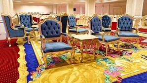 A banquet hall with rows of blue upholstered chairs and ornate gold tables, a red carpet, and a floral patterned carpet. - Royal Congress Hotel (Kyiv)