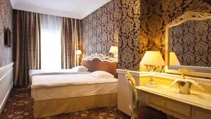 A hotel room with a double bed, a nightstand, a mirror, and a patterned carpet. - Royal Congress Hotel (Kyiv)