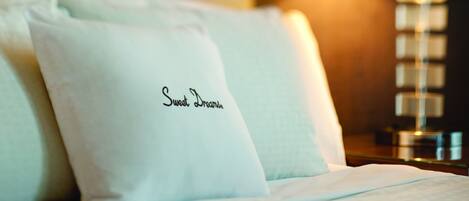 A neatly made bed with pillows, one of which has "Sweet Dreams" embroidered on it.