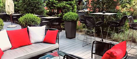An outdoor patio area with a sofa, chairs, and tables.