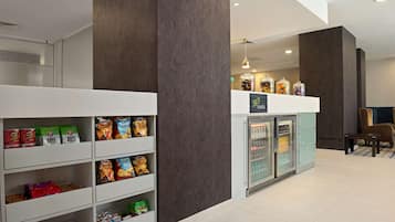 A snack bar with shelves stocked with various snacks and a refrigerator.