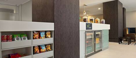 A snack bar with shelves stocked with various snacks and a refrigerator.