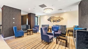 A hotel lobby with multiple seating areas, a chandelier, and a wall art piece.