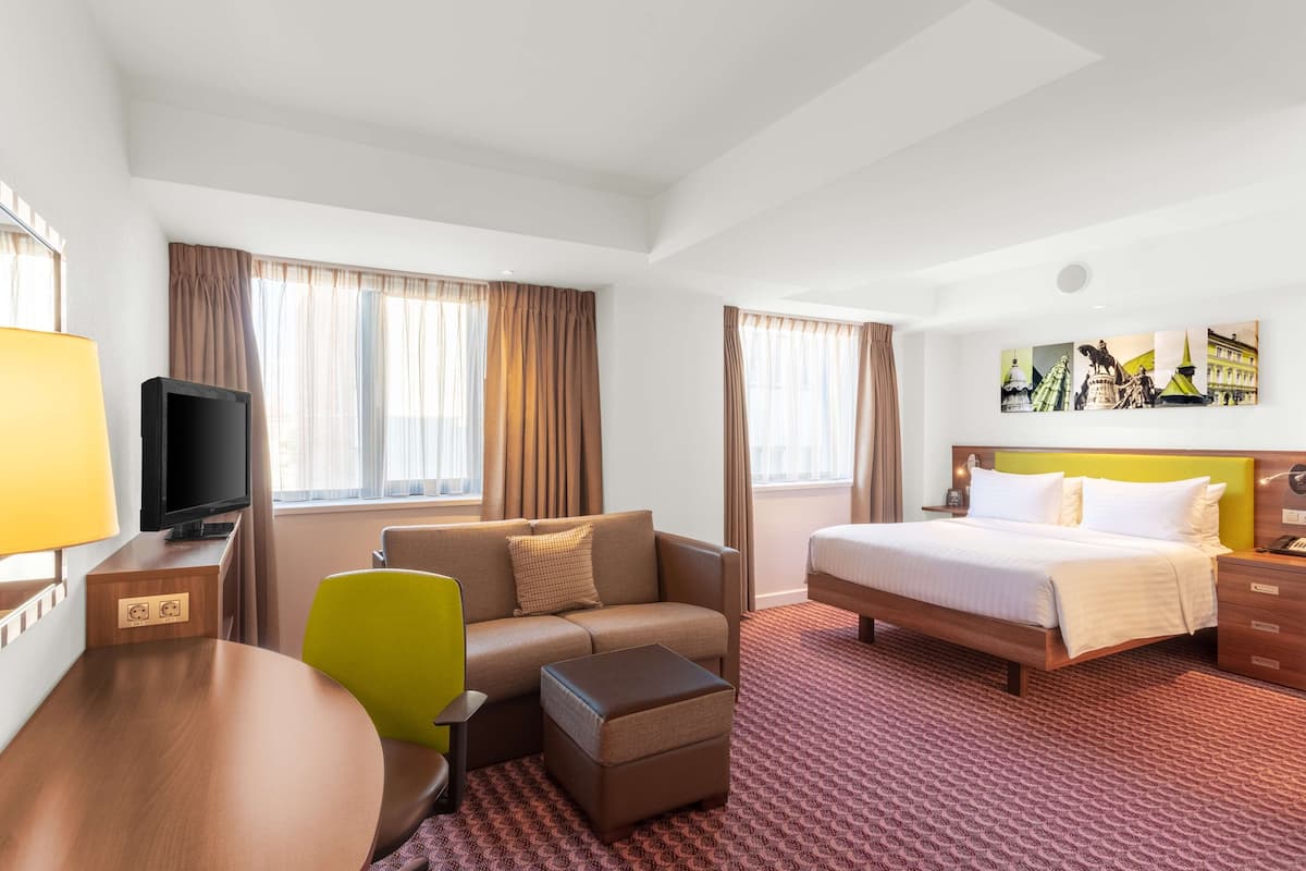 Une chambre d’hôtel avec un lit, un canapé, une télévision, un bureau et une chaise.