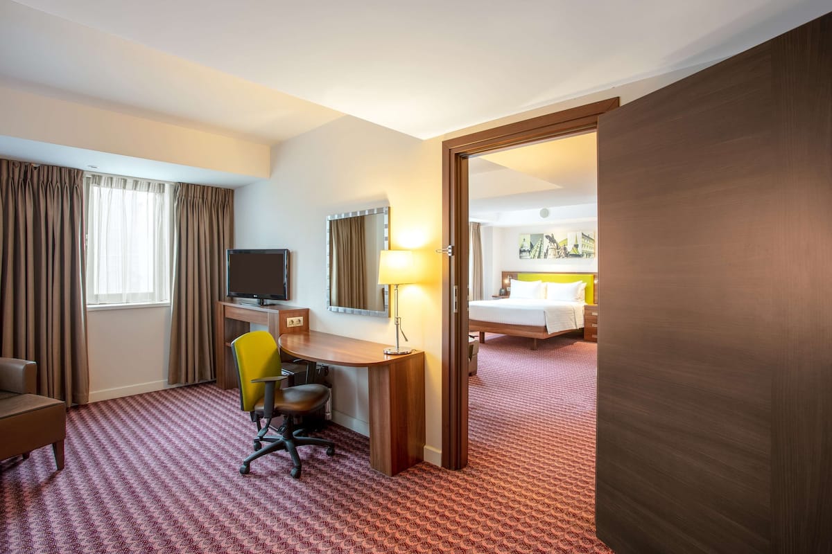 Une chambre d’hôtel équipée d’un bureau, d’une chaise, d’une télévision, d’une lampe et d’un lit.