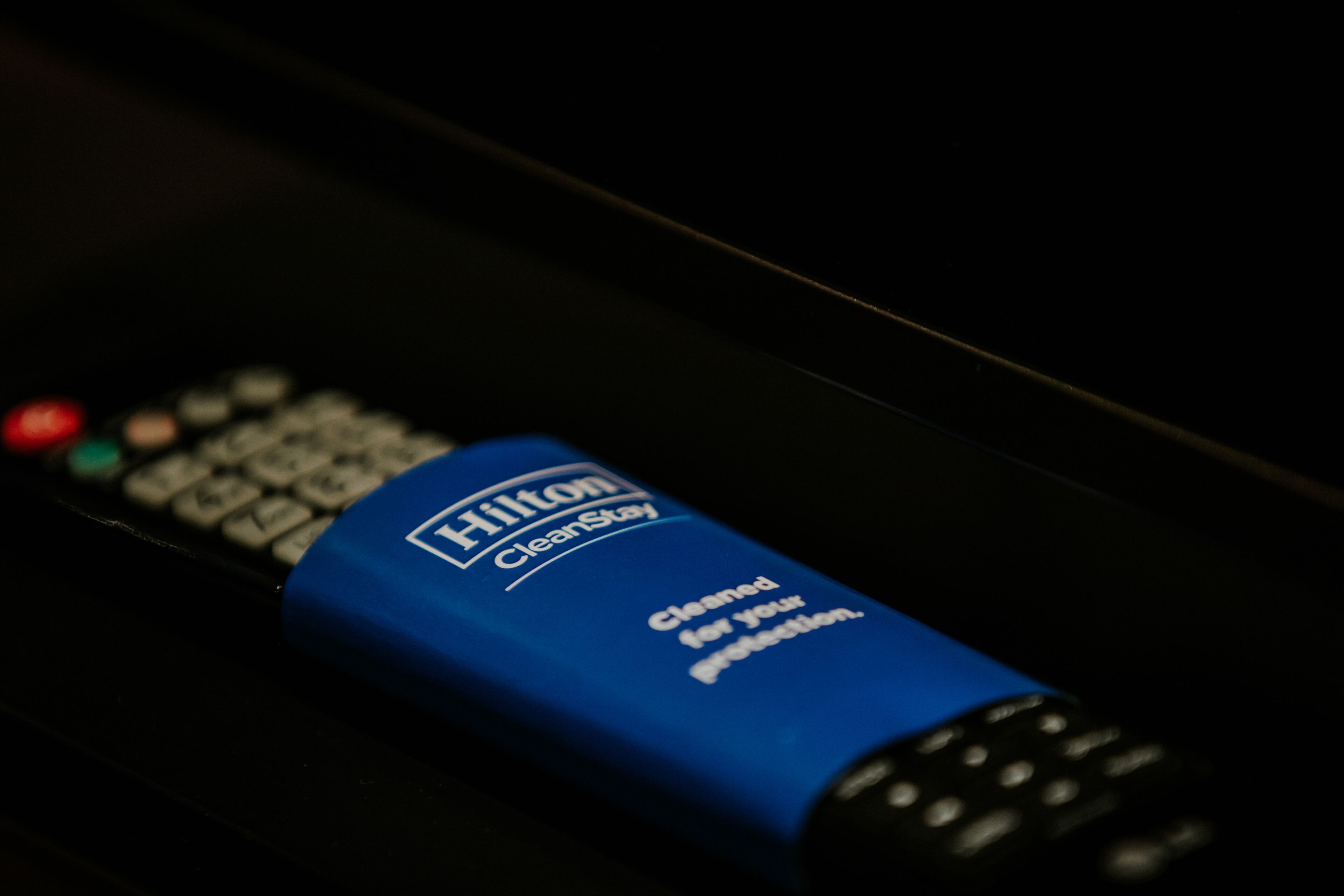 A blue Hilton CleanStay remote control on a dark surface.
