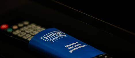 Un control remoto azul de Hilton CleanStay sobre una superficie oscura.