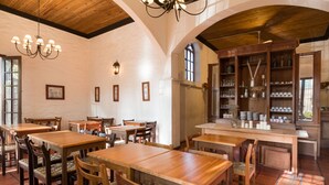 A restaurant with wooden tables and chairs, a bar area, and a tiled floor. - Don Antonio Posada (Colonia del Sacramento)