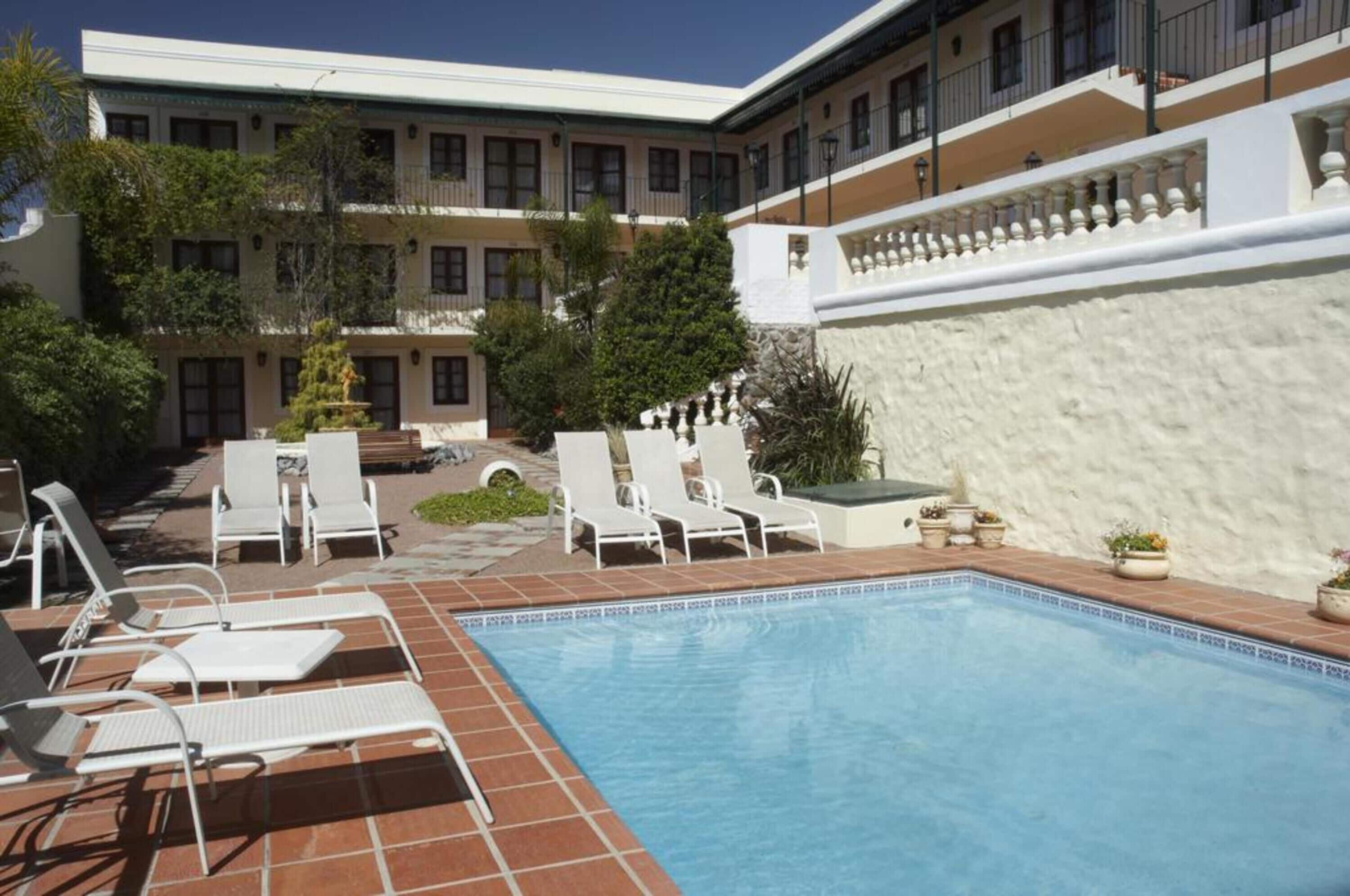 Un espace piscine avec des chaises longues et un bâtiment doté de nombreux balcons.