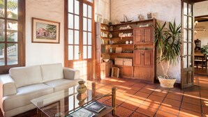 A spacious living area with a white sofa, a glass coffee table, and a wooden cabinet with shelves. - Don Antonio Posada (Colonia del Sacramento)