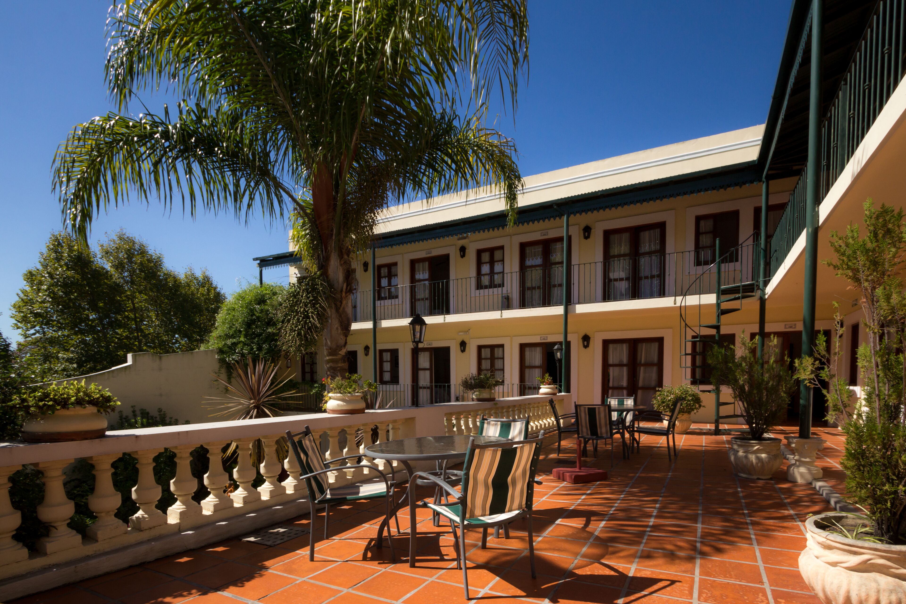 A courtyard with a tiled floor, outdoor seating area, and potted plants.
