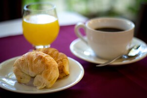 A breakfast setting with croissants, a glass of orange juice, and a cup of coffee on a table.