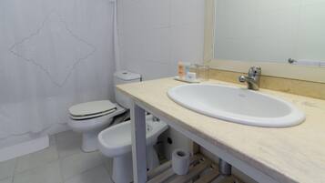 A bathroom with a white sink, toilet, and bidet.