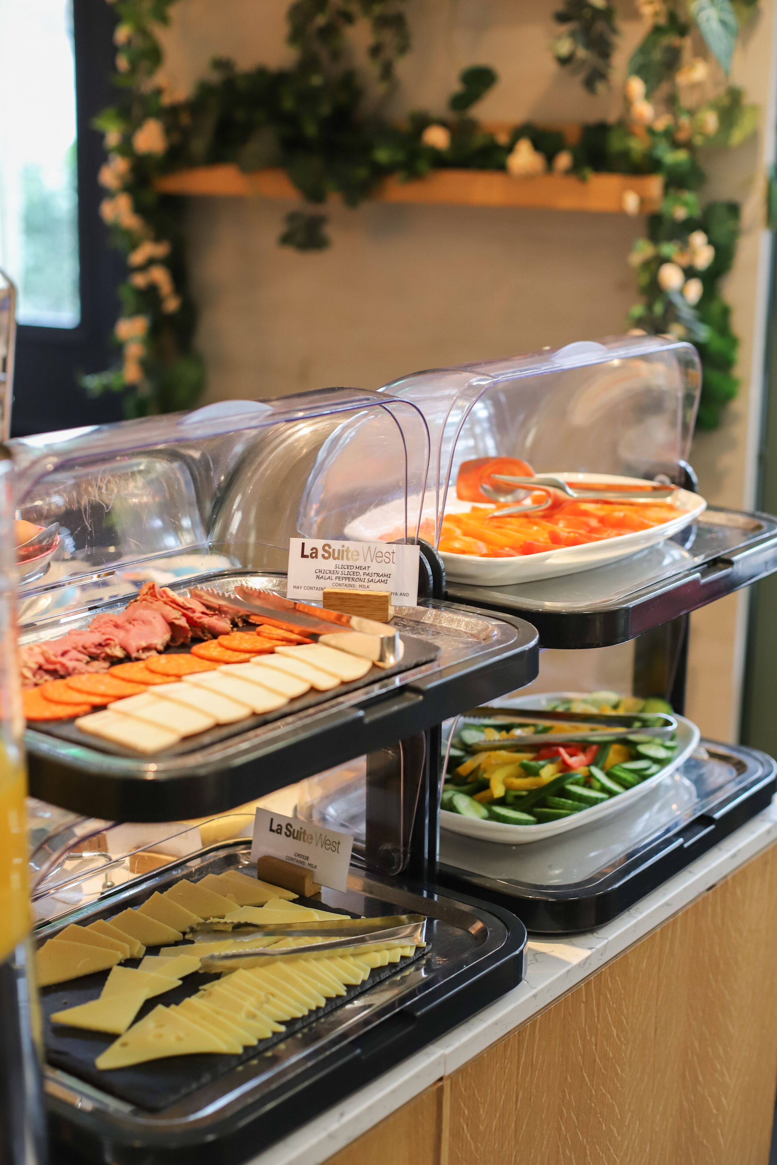 Un bufé con diversas opciones de comida, incluyendo carnes cortadas, quesos y verduras.