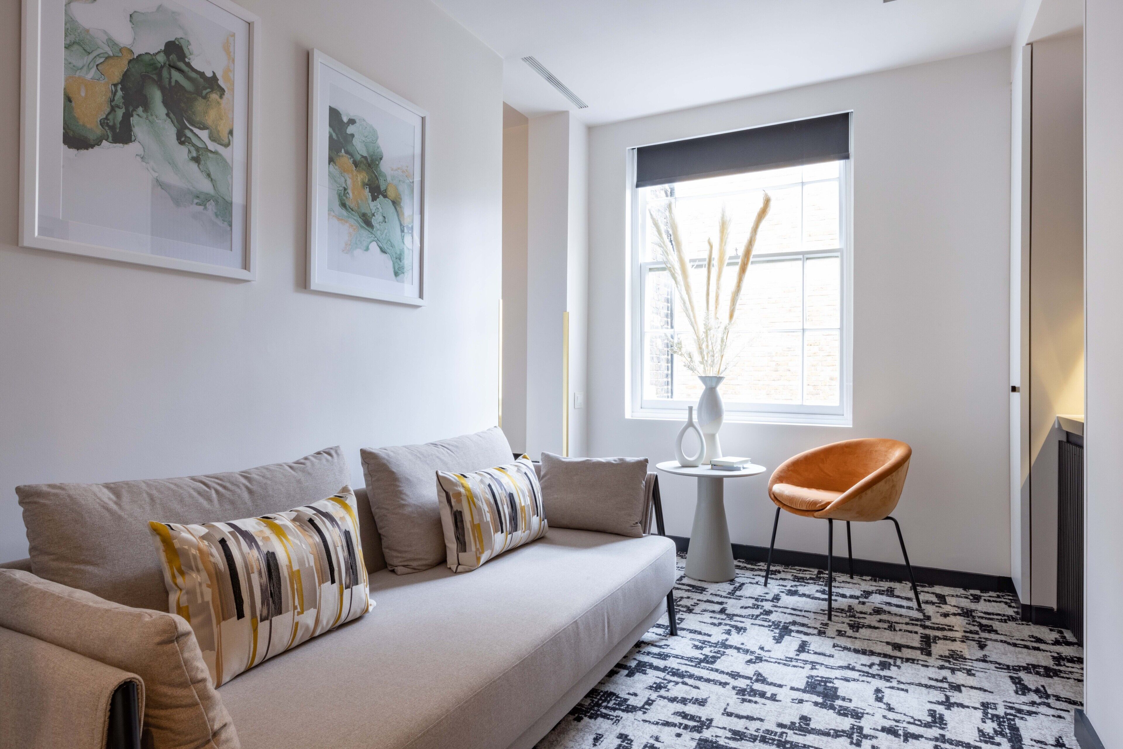 En moderne stue med sofa, dekorative puder, et sofabord, en vase og en lænestol.