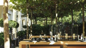 Un espace de restauration en plein air, avec des tables et des bancs en bois, entouré de verdure et d’arbres.