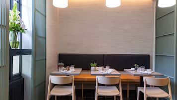Un restaurante con una decoración moderna, que presenta una larga zona de asientos tipo banco, mesas y sillas de madera.