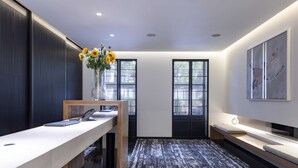Un espace d’accueil moderne, avec un comptoir de réception, un vase rempli de tournesols et un grand tableau abstrait accroché au mur.
