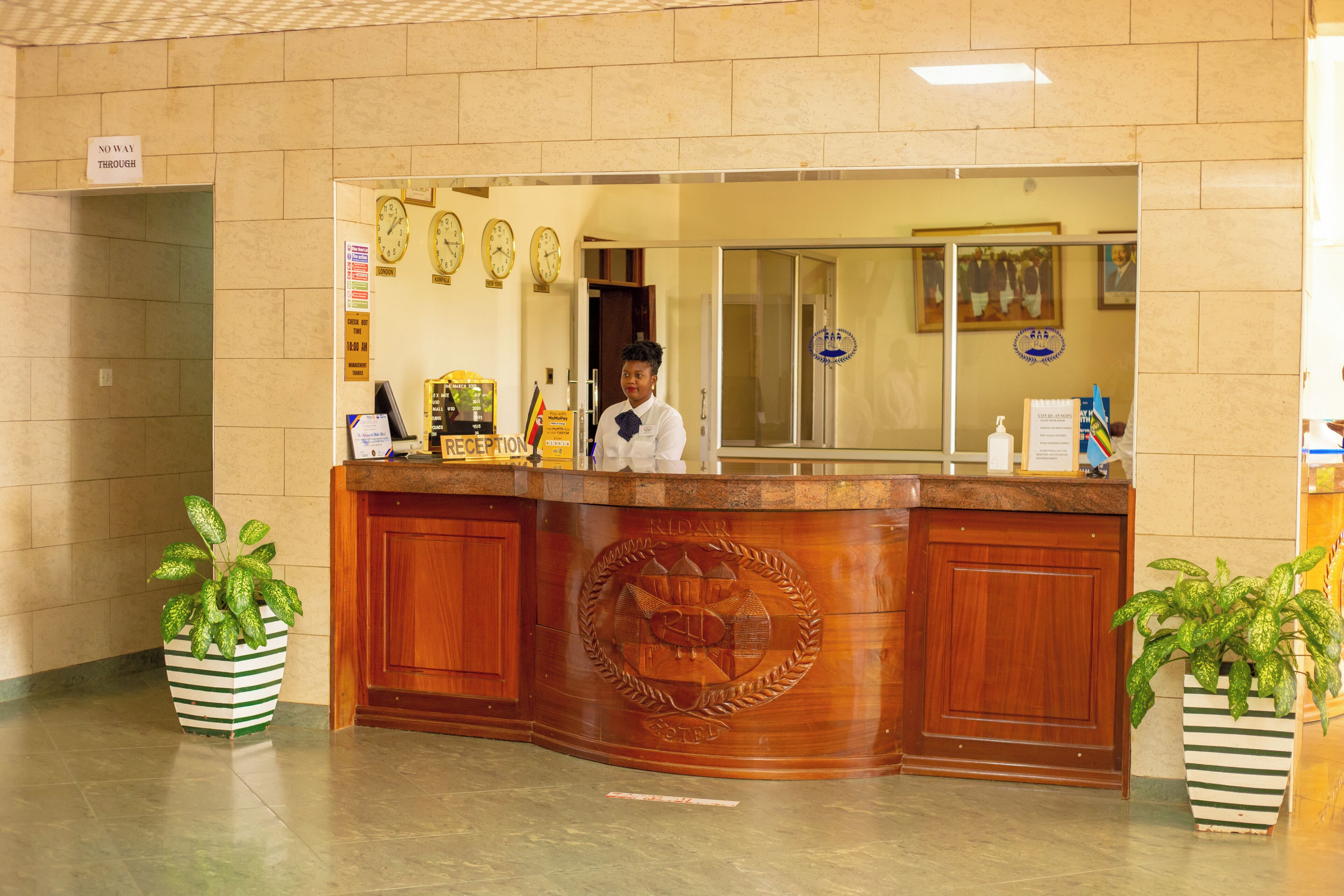 A reception desk with a clock, a sign reading "No Way Through," and two potted plants.