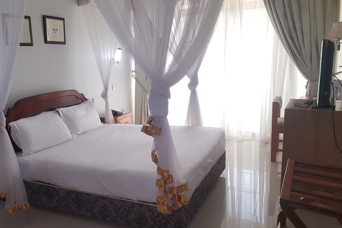 A neatly made bed with a wooden headboard, a bedside table, and a lamp.