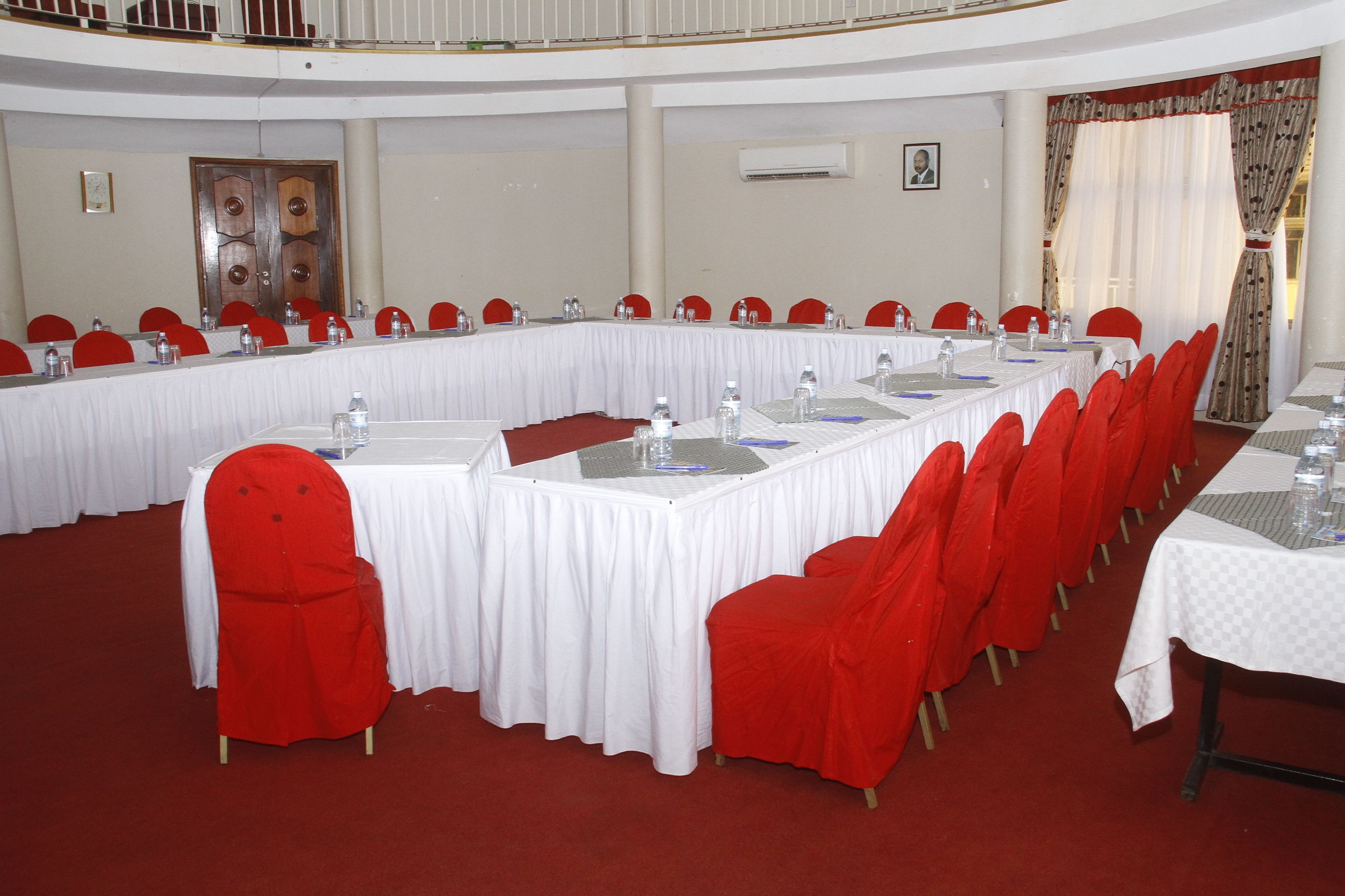 A conference room with a long table, red chairs, and white tablecloths.
