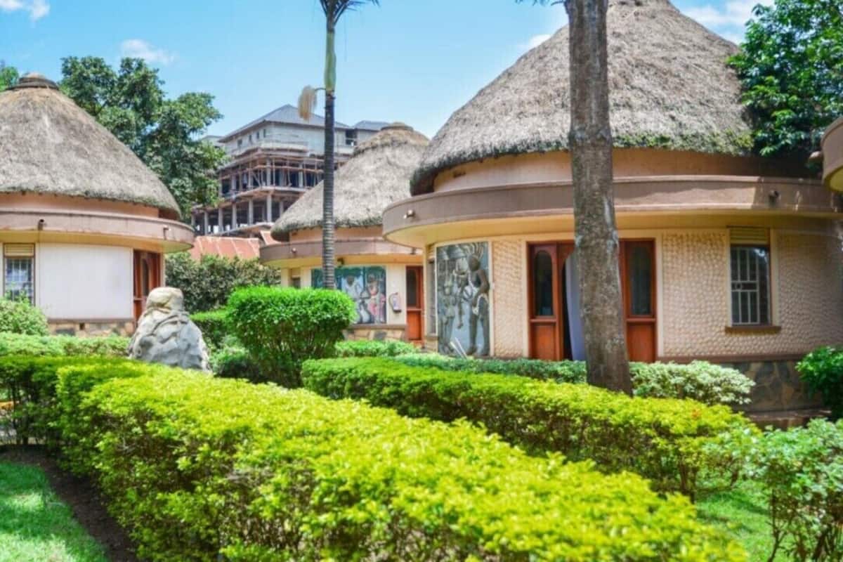 A resort with thatched-roof bungalows, manicured gardens, and a clear blue sky.