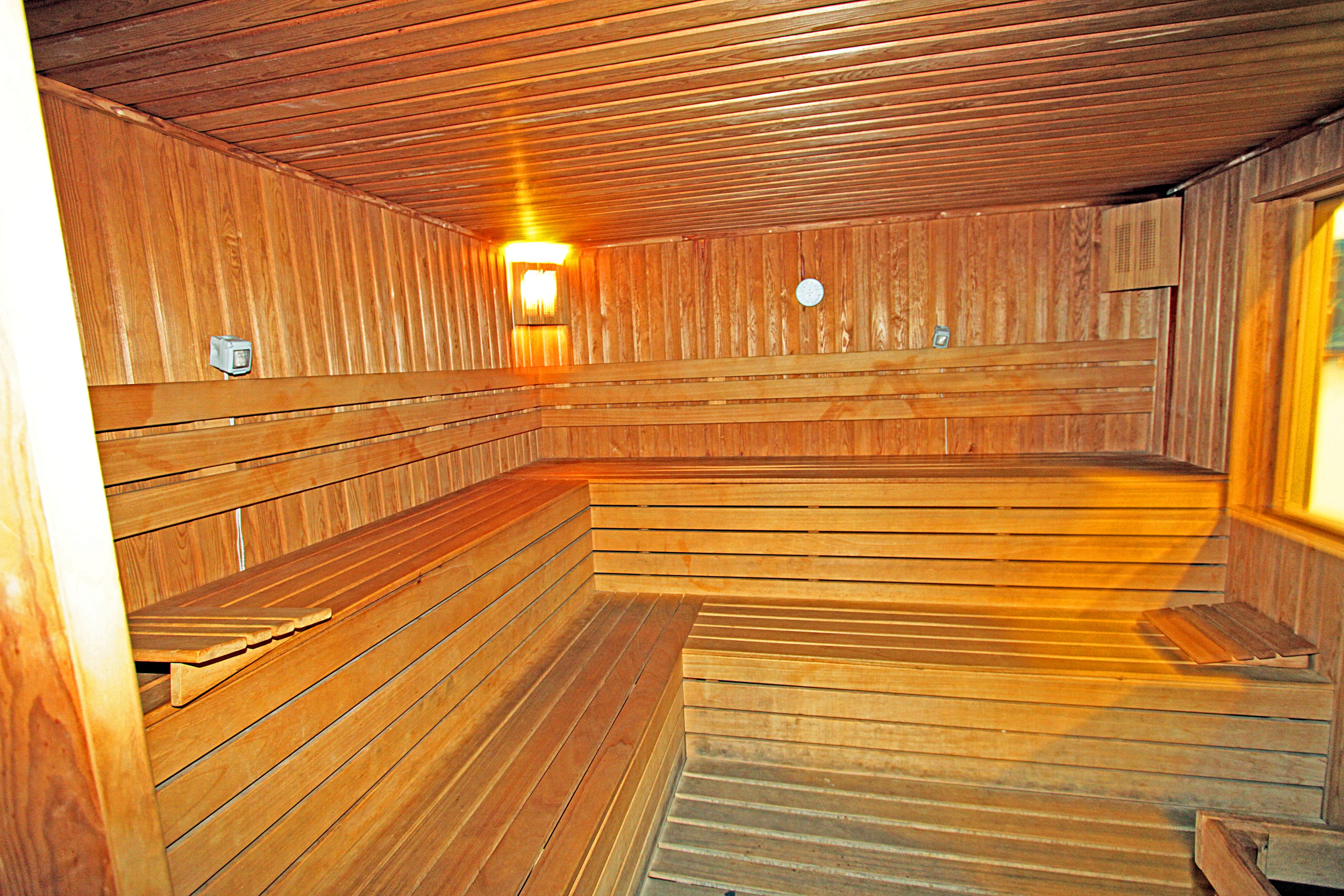 A wooden sauna with benches and a wall-mounted heater.