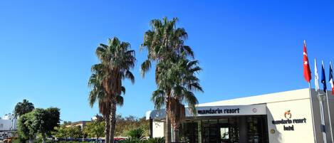 Un hôtel de la chaîne Mandarin Resort, avec un ciel d’un bleu éclatant, des palmiers et une enseigne.