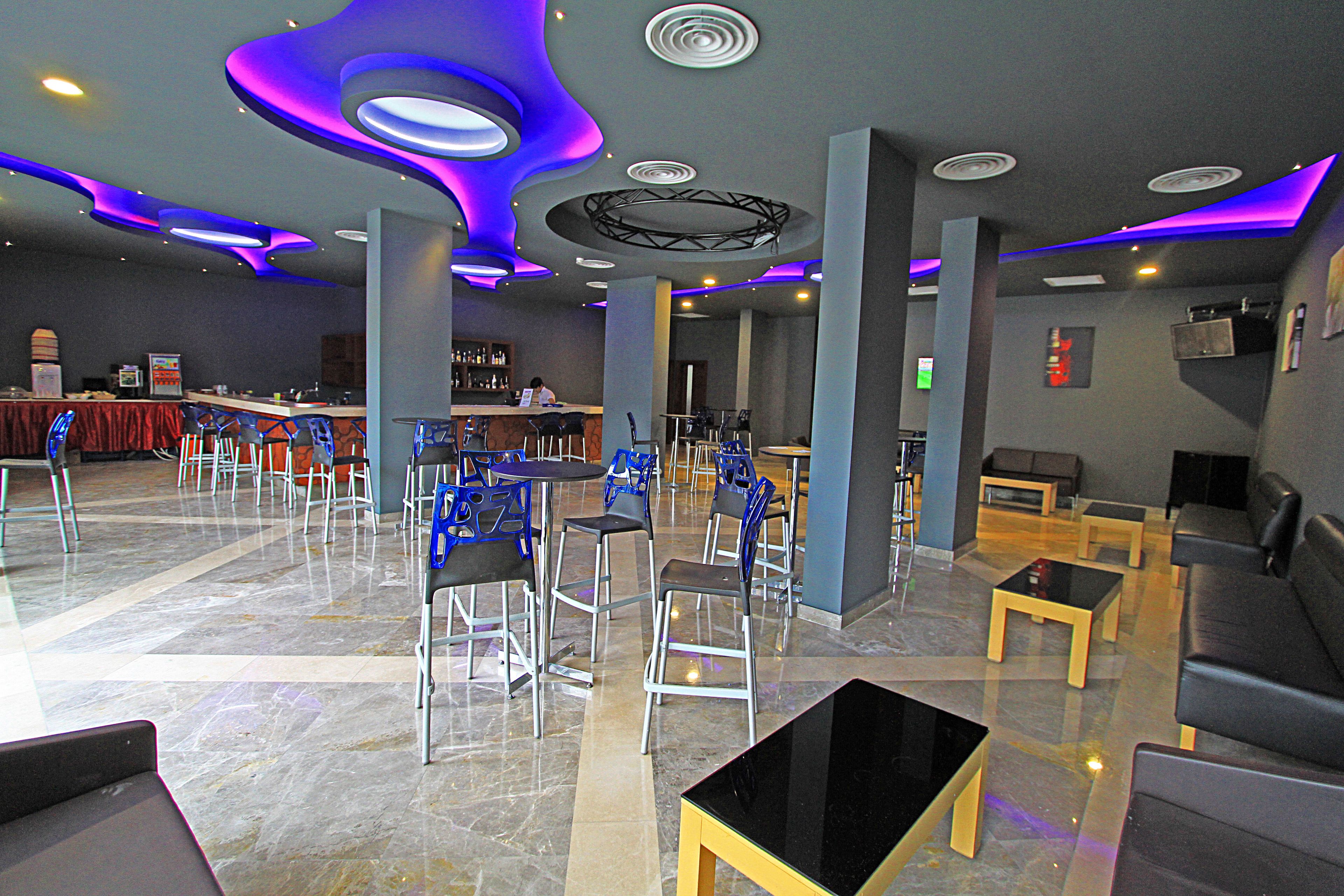 A modern hotel lobby with a bar area, seating arrangements, and a marble floor.