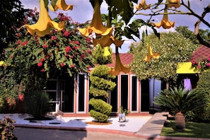 Stunning garden area with lush plants and flowers, surrounded by a modern building with a red-tiled roof and glass door entrance.