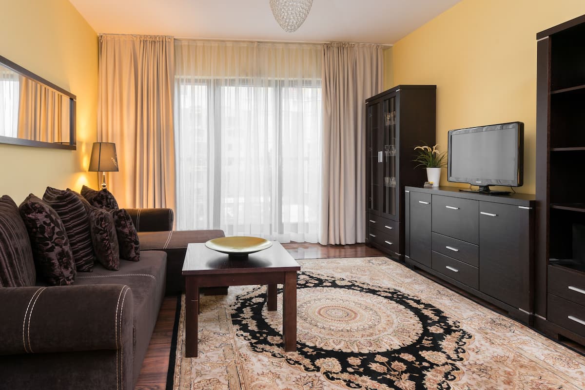 Uma sala de estar com sofá, mesa, televisão e armário.