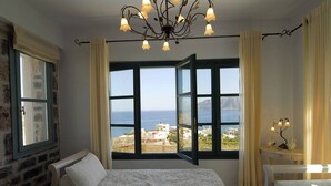A bedroom with a bed, a desk, and a view of the sea. - Mohlos Villas (Sitia)