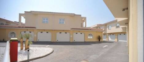 A building with multiple garage doors, a parking lot, and a clear sky.