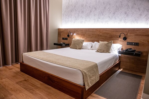 A neatly made bed with a wooden headboard, a bedside table with a lamp, and a power outlet.