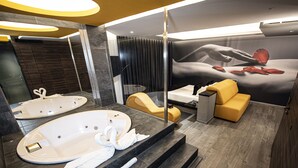Une salle de bain moderne dotée d’une grande baignoire, d’une douche séparée et d’un coin salon avec un fauteuil et un pouf jaunes.