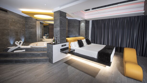 Une chambre d’hôtel moderne dotée d’un grand lit, d’une salle de bain séparée avec un jacuzzi et d’un coin salon.
