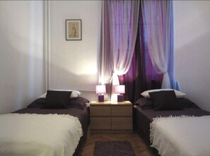 A room with two single beds, a nightstand with two lamps, and a window with sheer curtains. - Unique Warsaw Center Apartment (Warsaw)