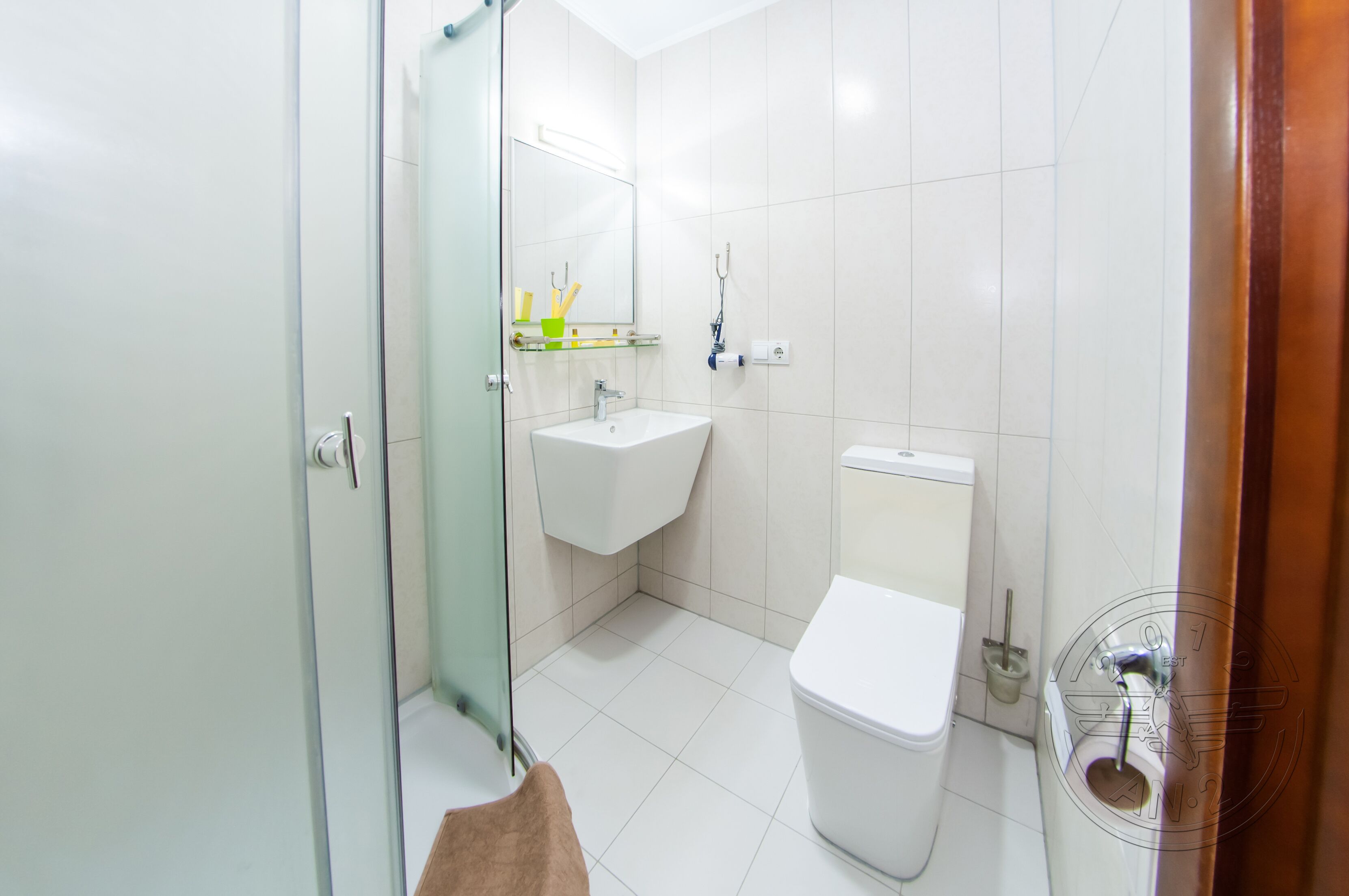A bathroom with a glass shower enclosure, a white sink, and a toilet.