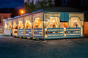 A row of outdoor seating areas with covered tables and chairs, separated by decorative lattice panels. - Antwo-Hotel (Kharkiv)